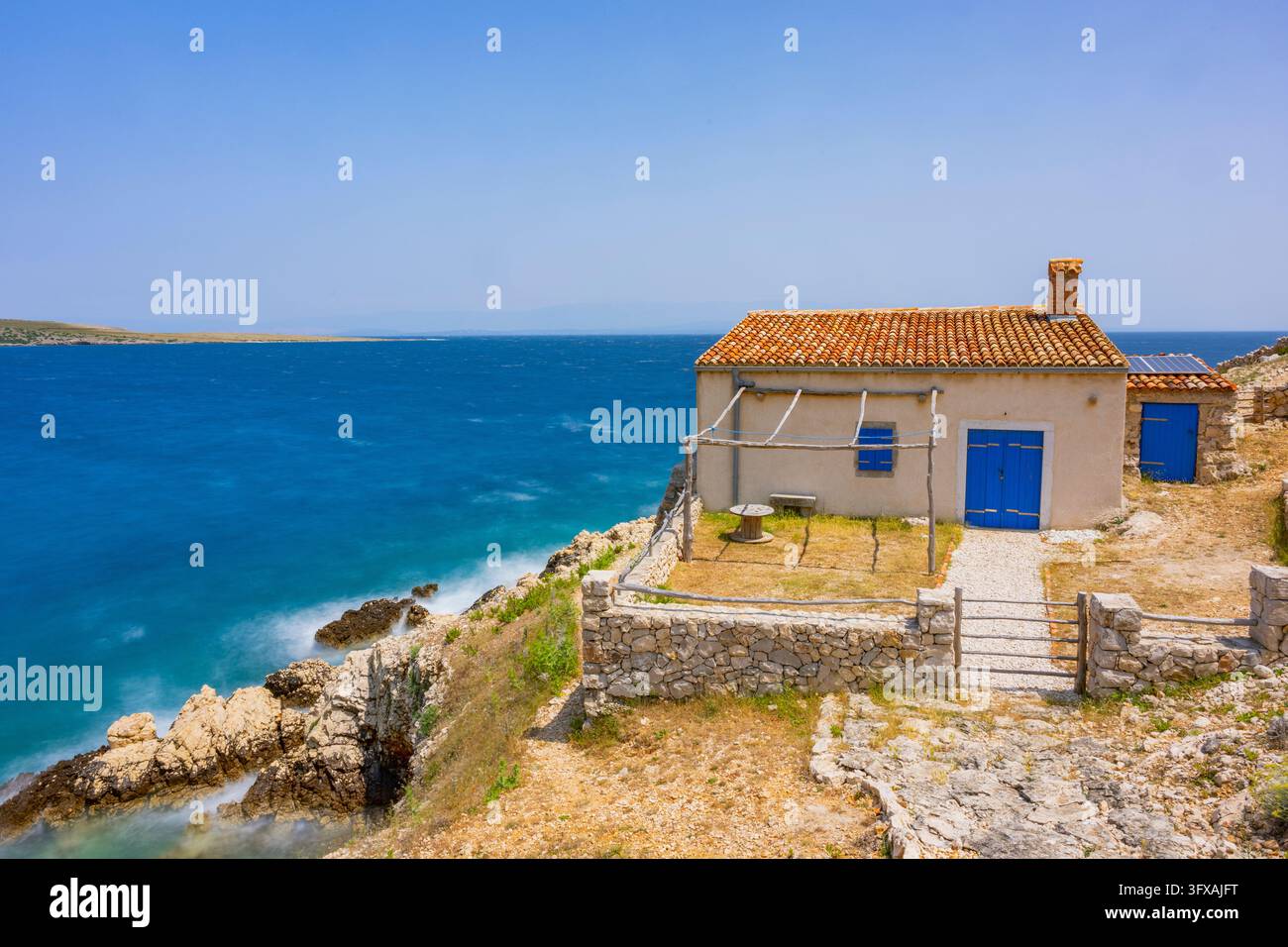 Piccola casa nella baia di Koromačna costruita sulle rocce sopra il mare con vista sul mare in una giornata soleggiata sull'isola di Cres, Croazia Foto Stock
