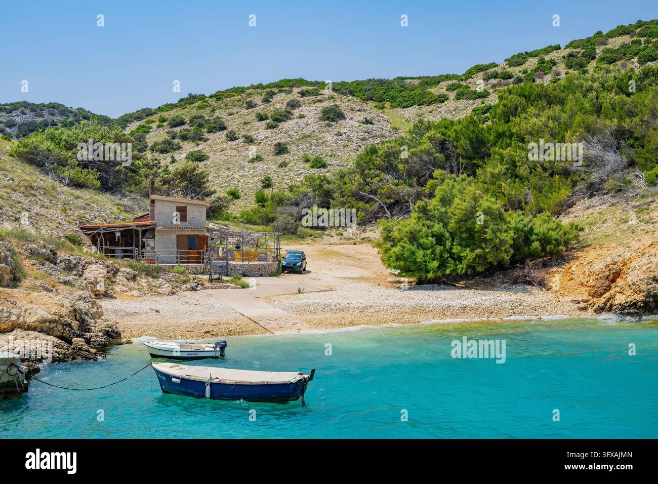 Piccola casa nella baia di Koromačna e barche sdraiate sul mare con vista sul mare in una giornata soleggiata sull'isola di Cres, Croazia Foto Stock