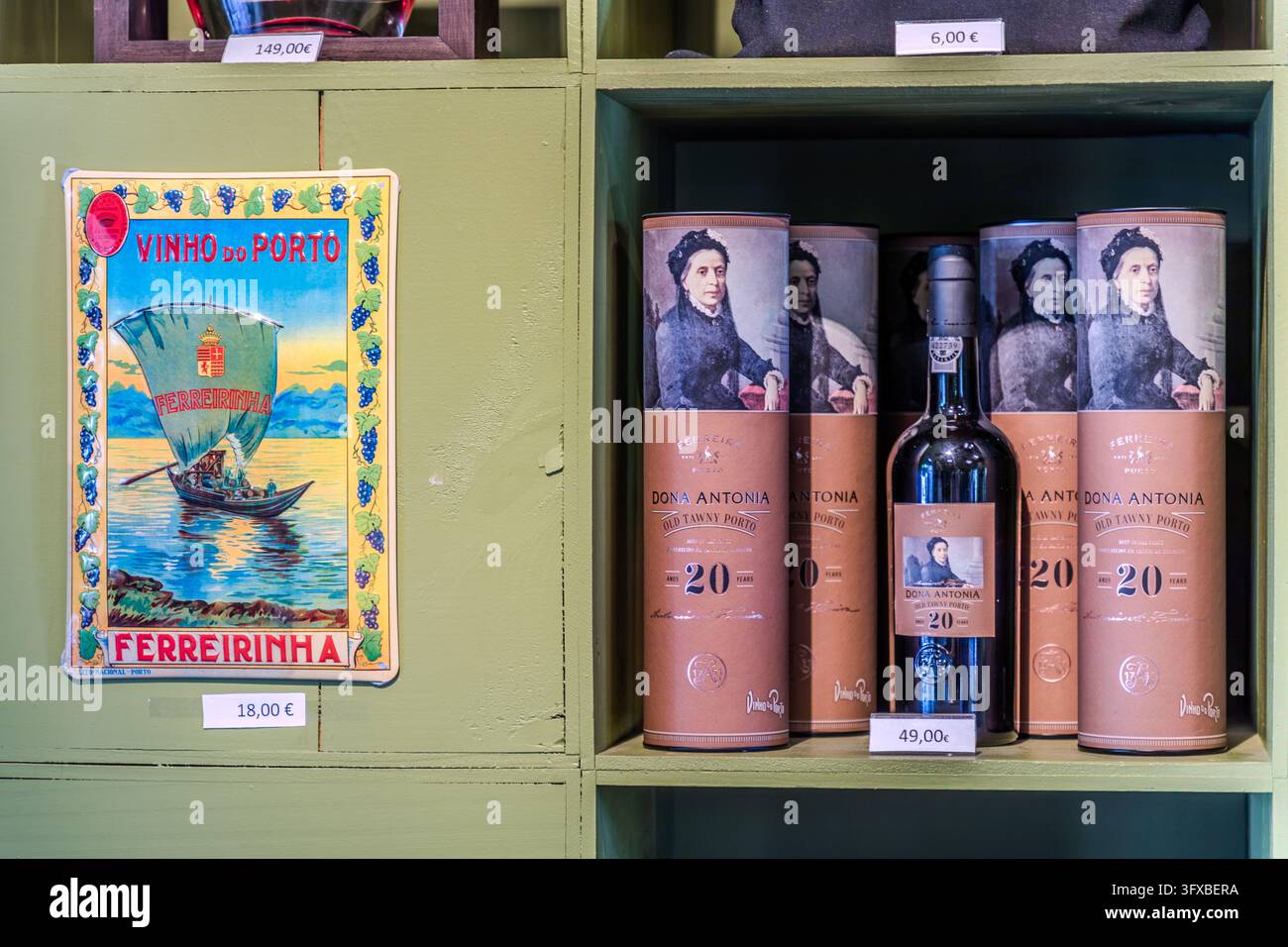 Uno scaffale in un negozio a Pinhão in Portogallo mostra vino porto della marca “Dona Antonia” (Old Tawny Porto, 20 anni). I tubetti e l’etichetta della bottiglia portano un ritratto di Dona Antónia Adelaide Ferreira. Un cartello di latta “Vinho do Porto – Ferreirinha” (vino porto – Ferreirinha) con una barca a vela è appeso a sinistra. Antónia Adelaide Ferreira (1811-1896), conosciuta come Ferreirinha, rimase vedova a 33 anni e gestì le proprietà familiari. Foto Stock
