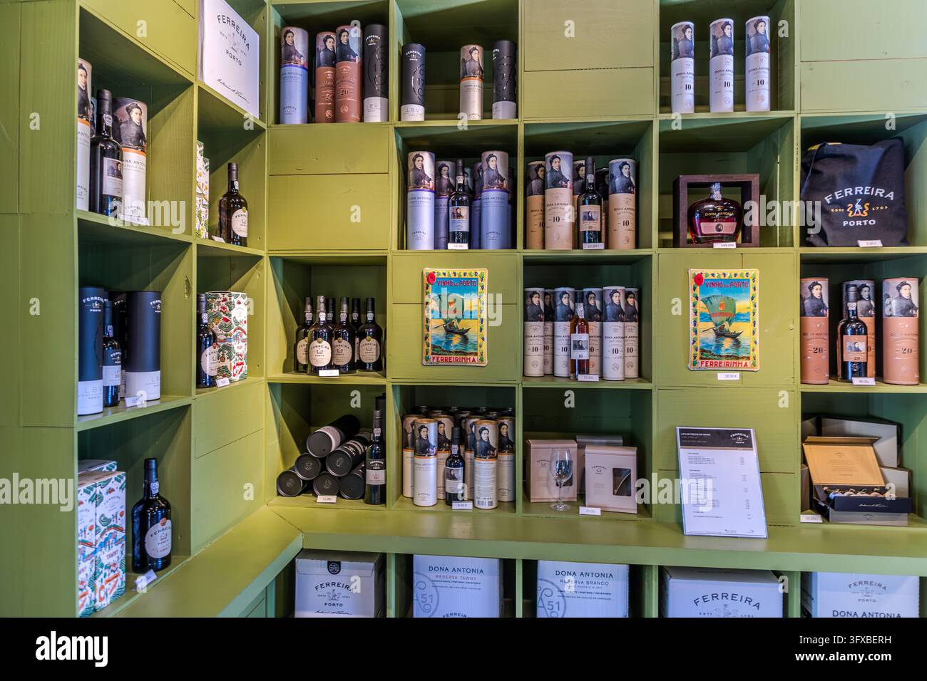 Scaffali di legno verde in un negozio di Pinhão in Portogallo sono pieni di vino Porto in tubi e cartoni. Le confezioni portano i nomi “Ferreira Porto” e “Dona Antonia”. Due cartelli di latta “Vinho do Porto” (vino Porto) sono appesi tra i compartimenti. La casa di Ferreira esiste dal 1751. Antónia Adelaide Ferreira (1811-1896), conosciuta come Ferreirinha, rimase vedova a 33 anni e gestì le proprietà familiari. Foto Stock