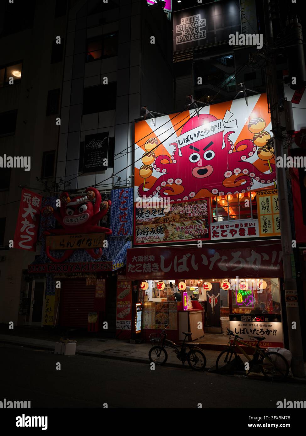 Ristoranti Takoyaki con enormi cartelli a forma di polpo su una strada di notte, Osaka. Foto Stock