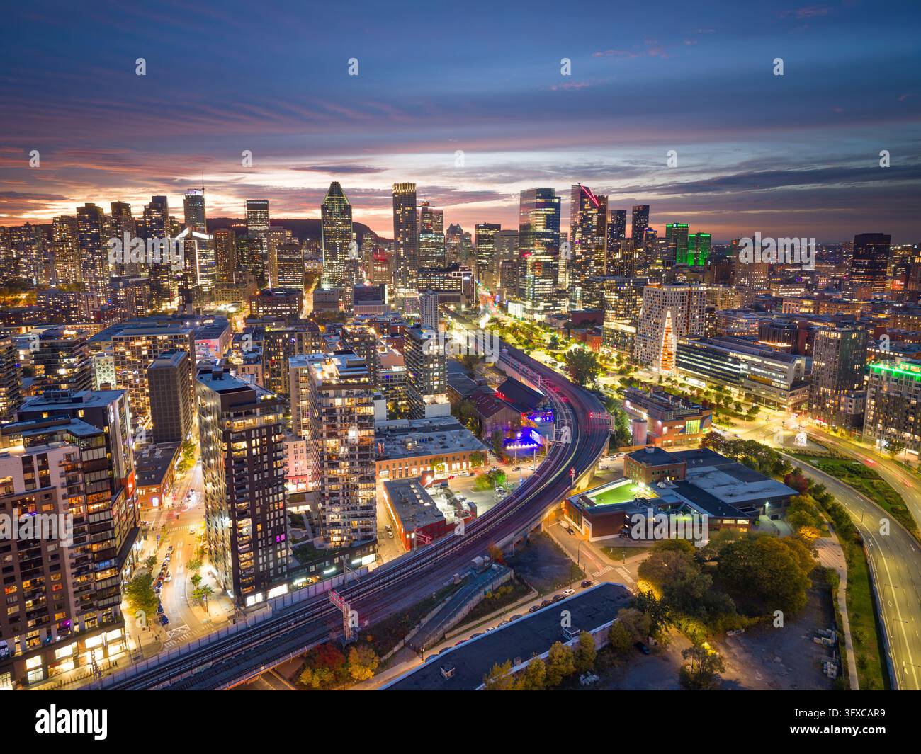 Montreal, Quebec, Canada, skyline della città al crepuscolo sopra le linee ferroviarie e un'infrastruttura densa. Foto Stock