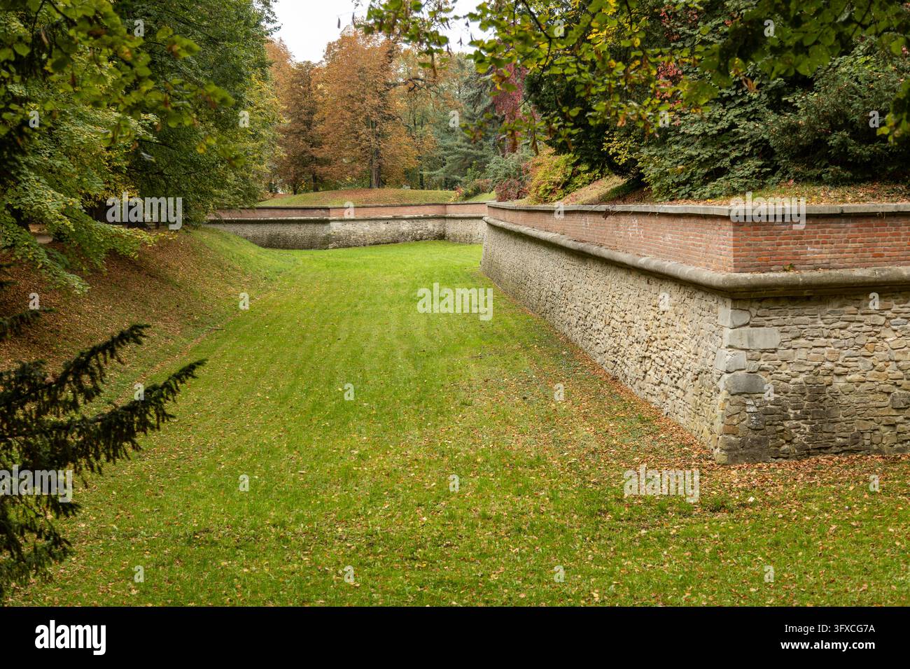 Un fossato asciutto e mura difensive storiche si snodano attraverso il parco autunnale che circonda il Castello di Lancut in Polonia. Foto Stock