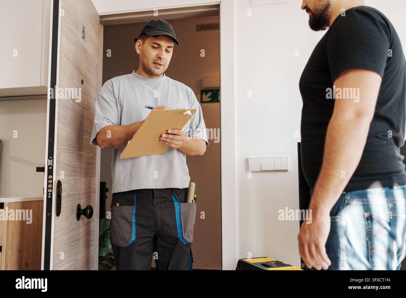 Proprietario e tecnico effettuano un controllo formale con documentazione e appunti di ispezione all'ingresso Foto Stock