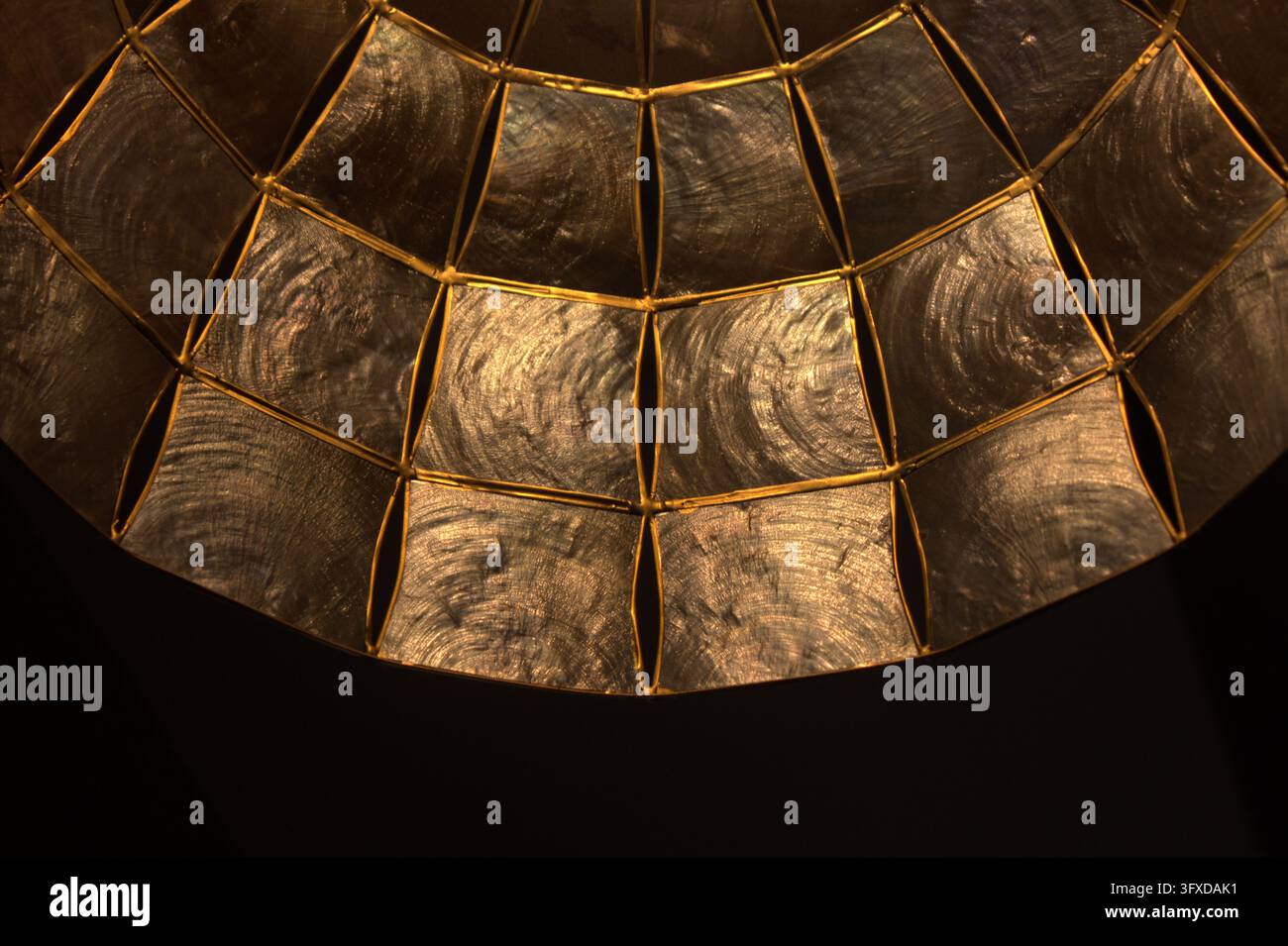 Una bellissima vista astratta in primo piano di un paralume a mosaico scuro con linee metalliche dorate e ombre. Foto Stock