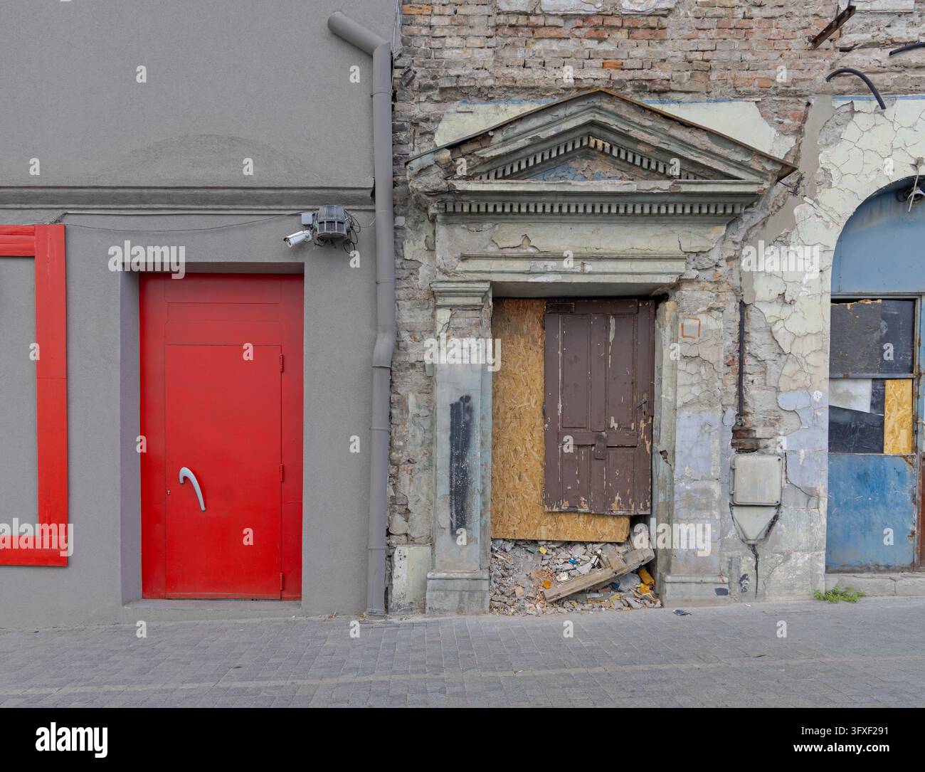 Nuova porta rossa e ingresso sbarrato di una rovina di edificio abbandonato nel centro città Foto Stock