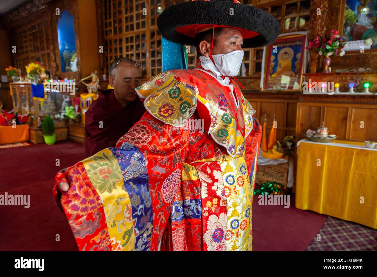 Lama che prepara la danza dei cappelli allargando le maniche della sua veste di broccato con un monaco dietro di lui, Ladakh, Leh, India Foto Stock
