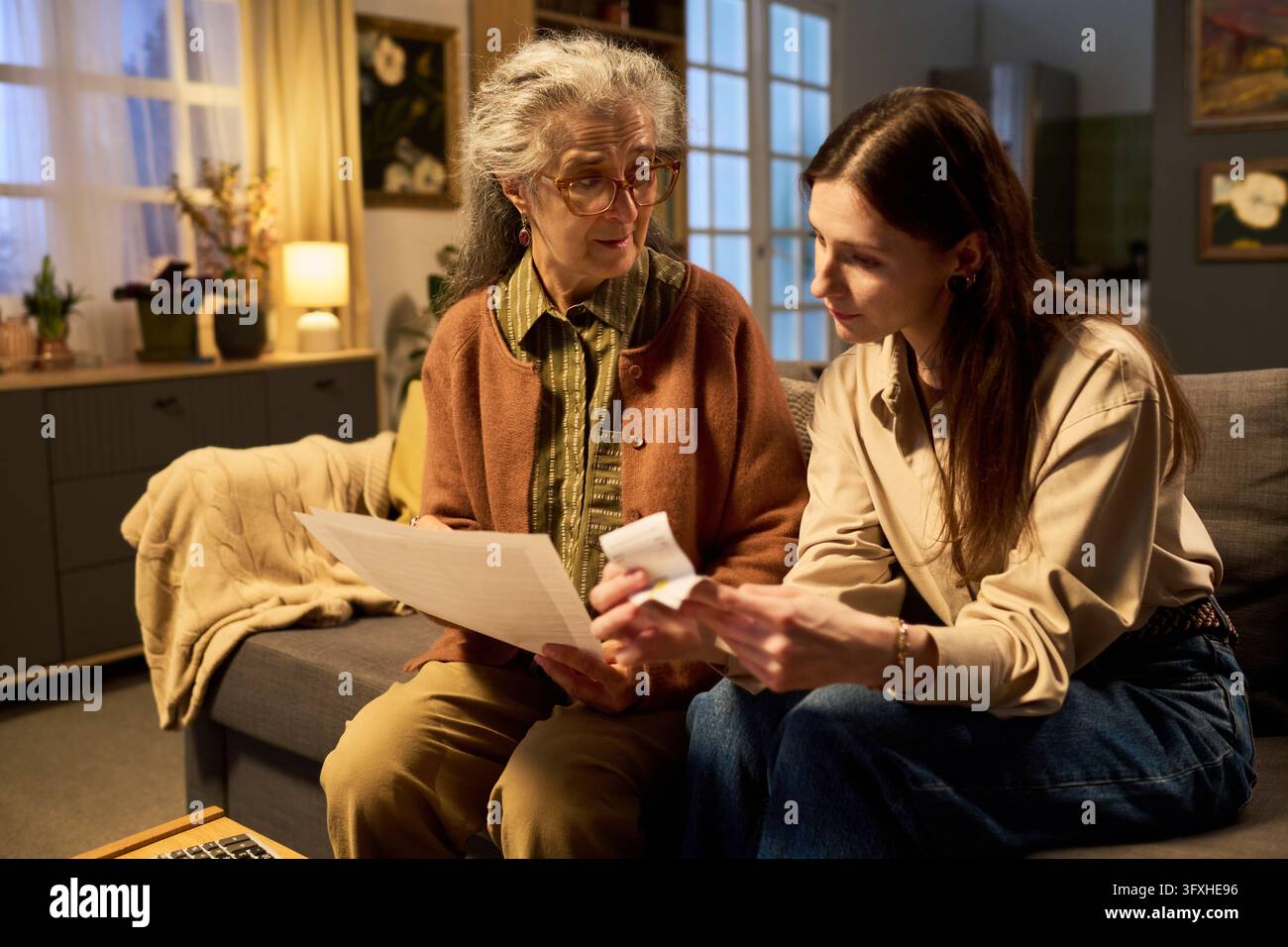 Giovane donna che aiuta la madre anziana a controllare le bollette domestiche a casa Foto Stock
