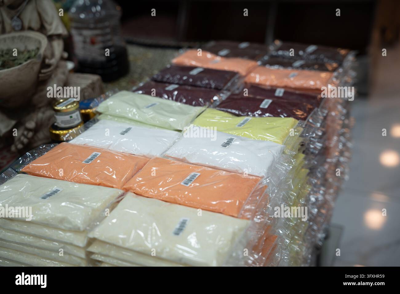 Confezioni sigillate impilate di prodotti secchi in polvere colorati in una bancarella del mercato egiziano. Acquisti nei mercati locali al dettaglio di alimenti e commercio tradizionale. Foto Stock