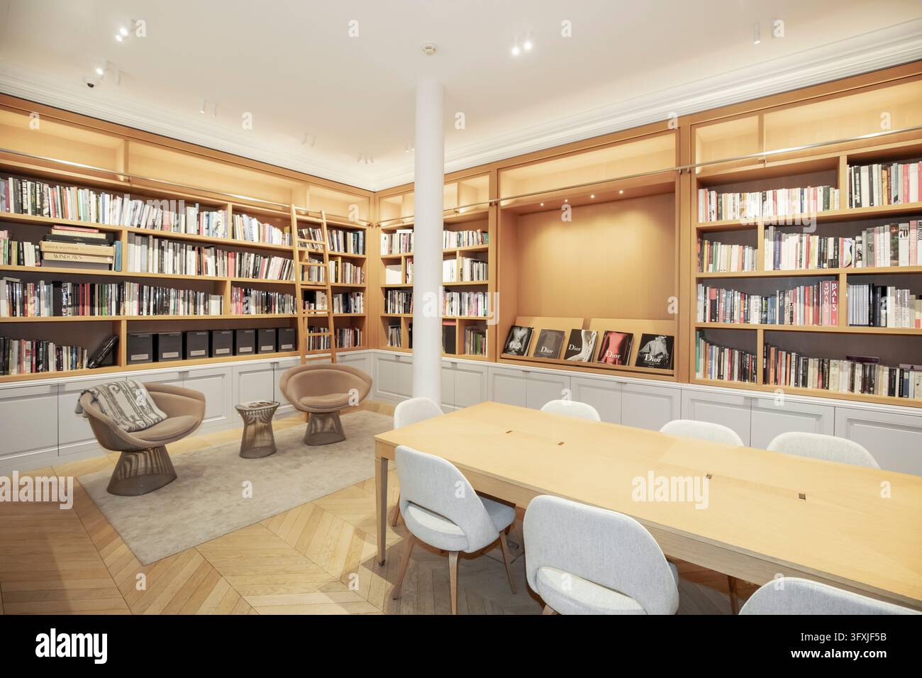Dentro la biblioteca dell'archivio Dior Héritage a Parigi, con scaffali in legno su misura, un tavolo da ricerca e poltrone lounge moderne di metà secolo Foto Stock