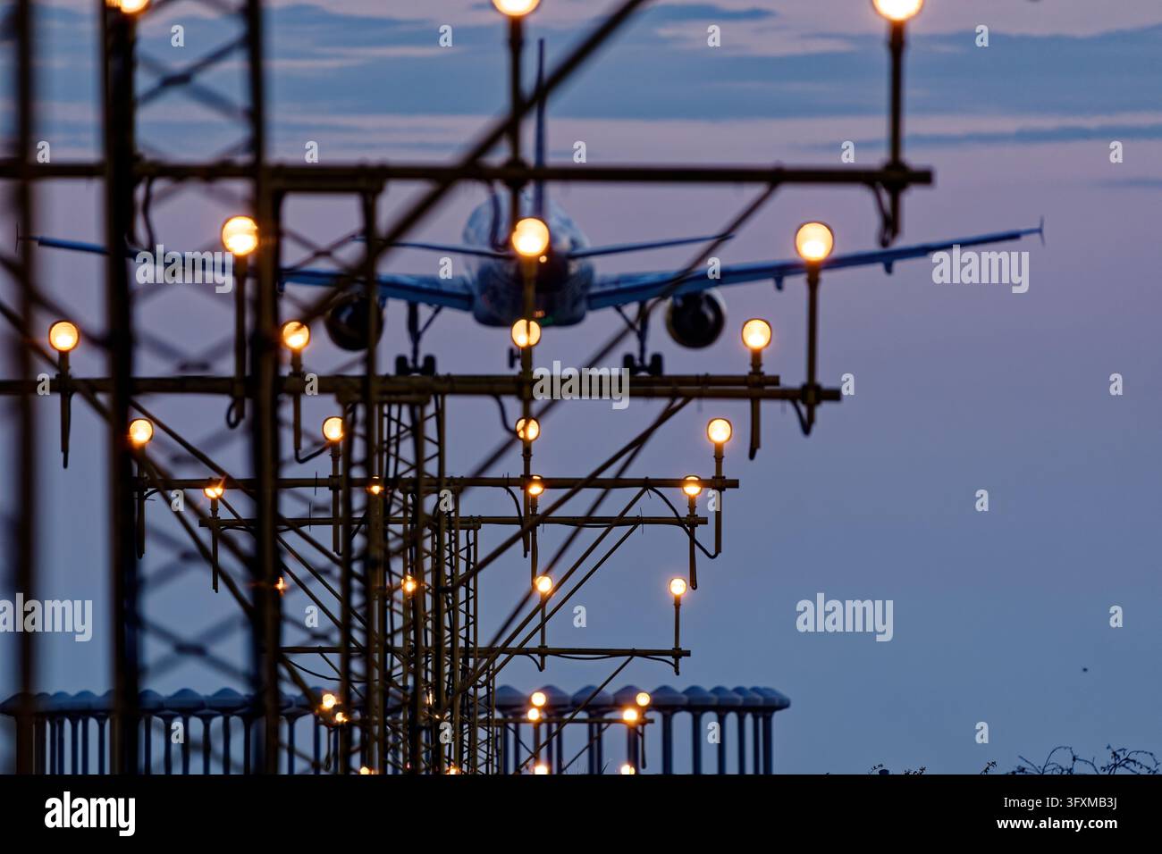 Sistema di illuminazione per l'avvicinamento alla pista con aereo in fase di atterraggio al crepuscolo Foto Stock