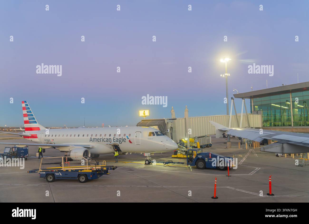 Oklahoma, Stati Uniti, 22 NOV 2024 - Un jet regionale American Eagle è parcheggiato a un gate con personale di terra e carrelli per i bagagli visibili sulla pista. Foto Stock