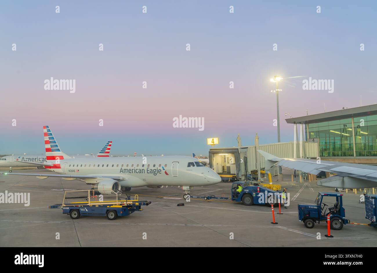 Oklahoma, Stati Uniti, 22 nov 2024 - Un jet regionale American Eagle è parcheggiato a un gate con il personale di terra e i carrelli bagagli visibili sulla pista Foto Stock