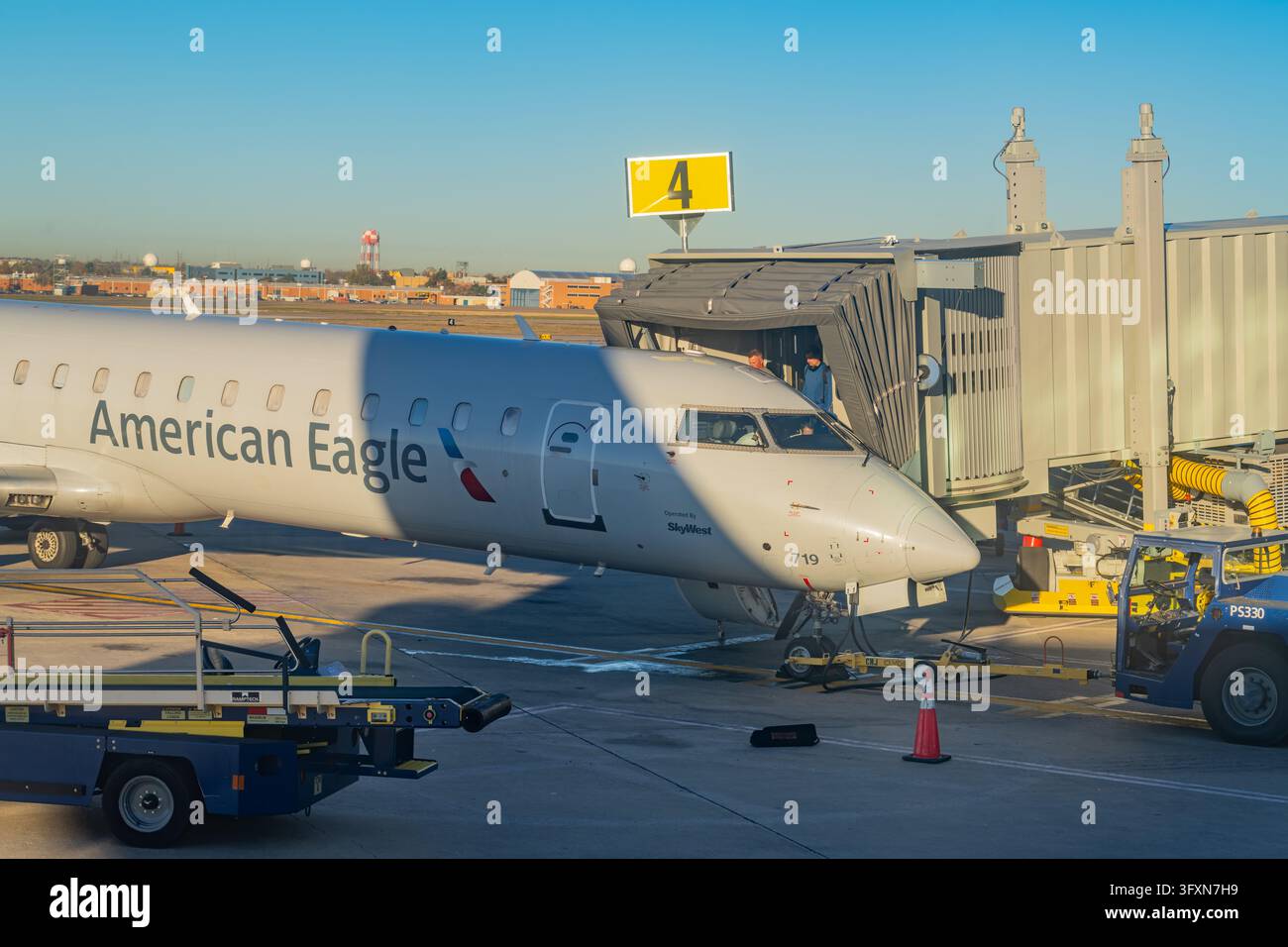 Oklahoma, Stati Uniti, 22 NOV 2024 - Un jet regionale American Eagle è parcheggiato al gate 4, collegato a una passerella, con attrezzature di supporto a terra v Foto Stock