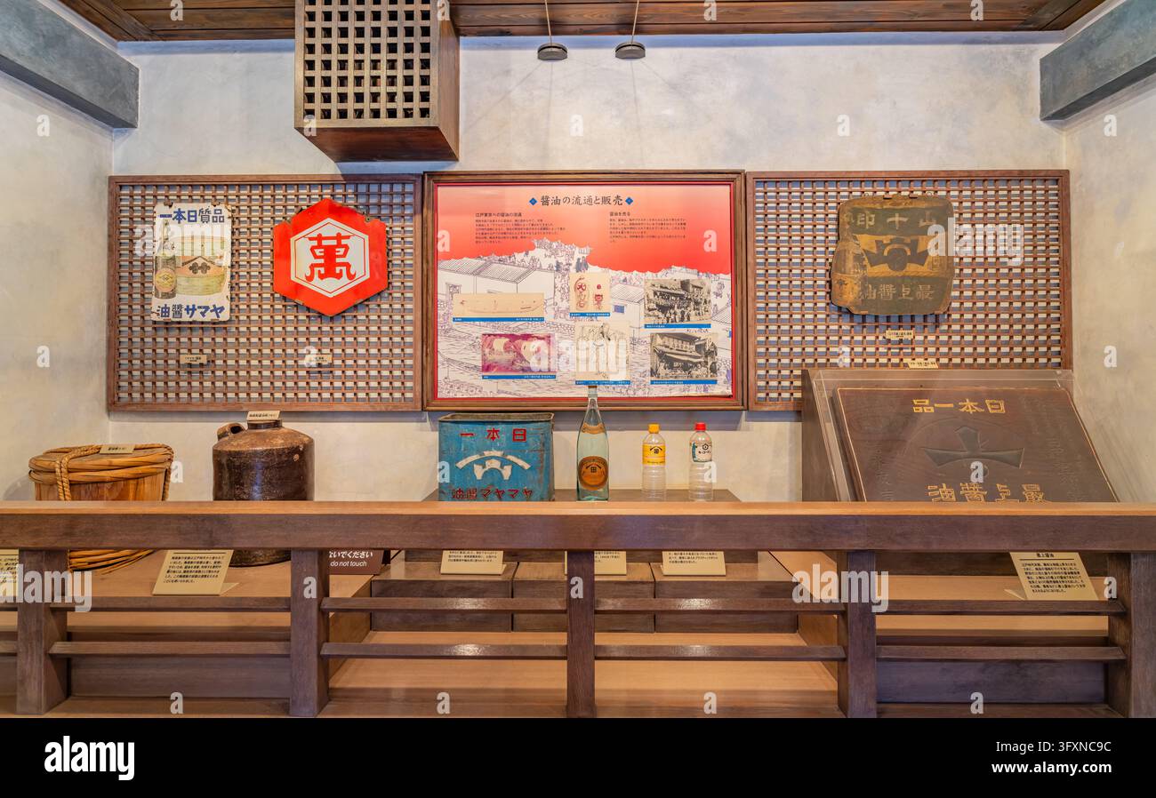 Tokyo, Giappone, 22 NOV 2024 - Una mostra museale presenta contenitori antichi di salsa di soia, casse di legno e pannelli informativi sulla storia della soia Foto Stock