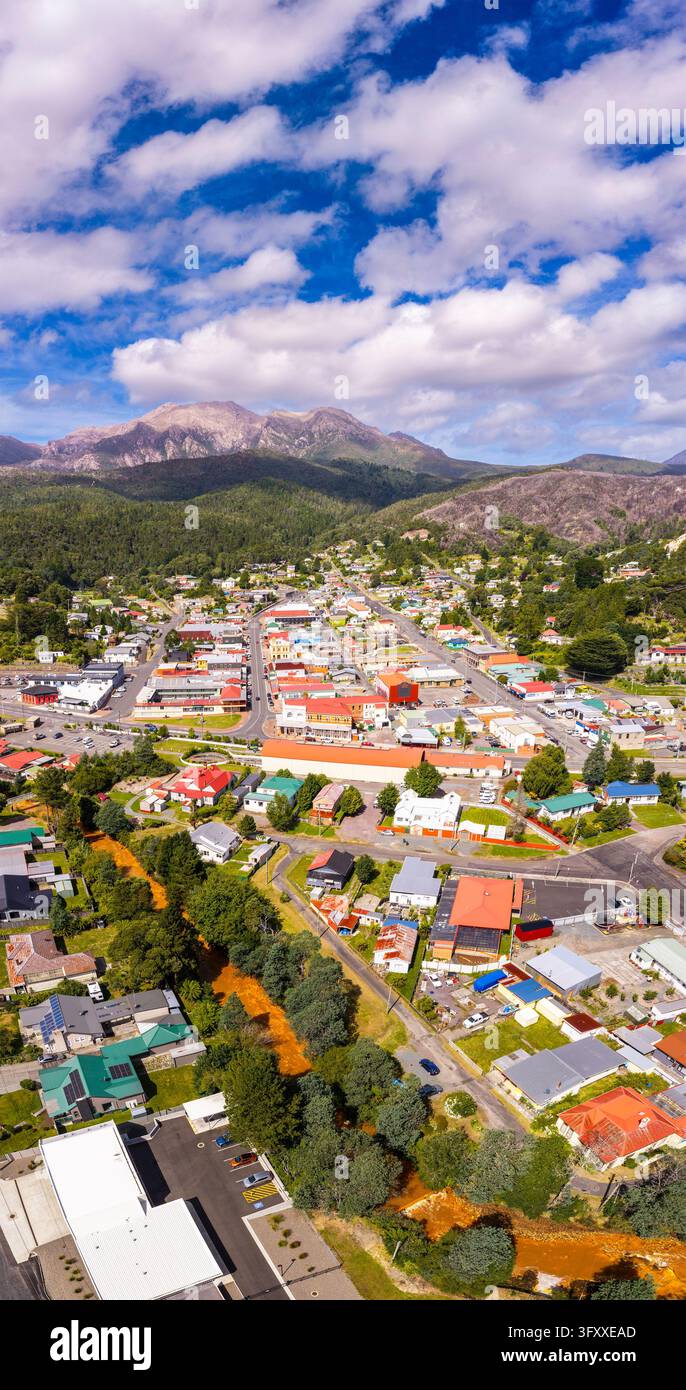 Dalla montagna di rame Queen River fino al Monte Owen attraverso il centro storico di Queenstown – panorama verticale aereo ravvicinato. Foto Stock
