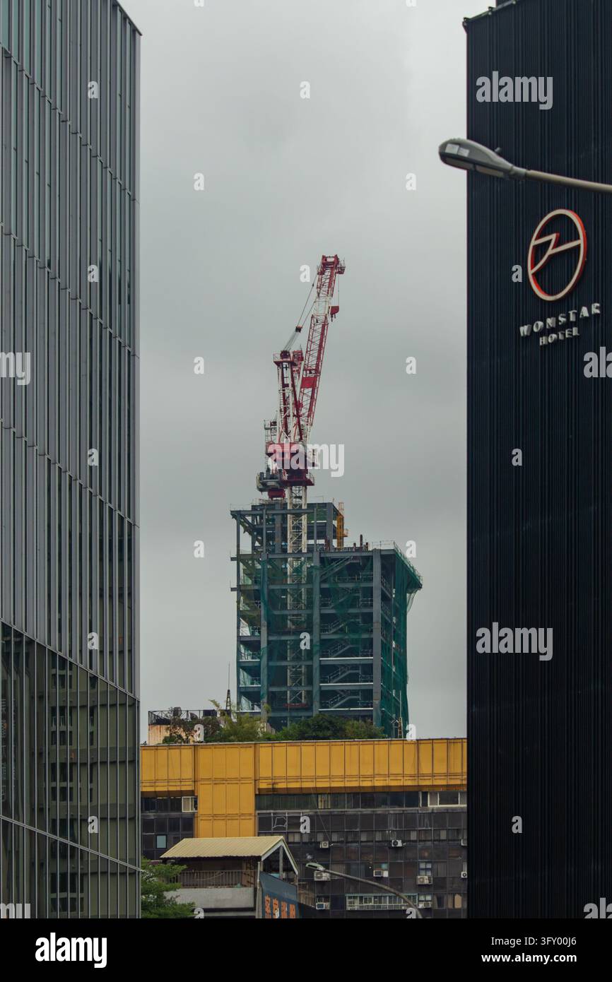 TAIPEI, TAIWAN - 13 DICEMBRE 2025: Un grattacielo in costruzione con una gru rossa è incorniciato tra edifici moderni della città. Foto Stock