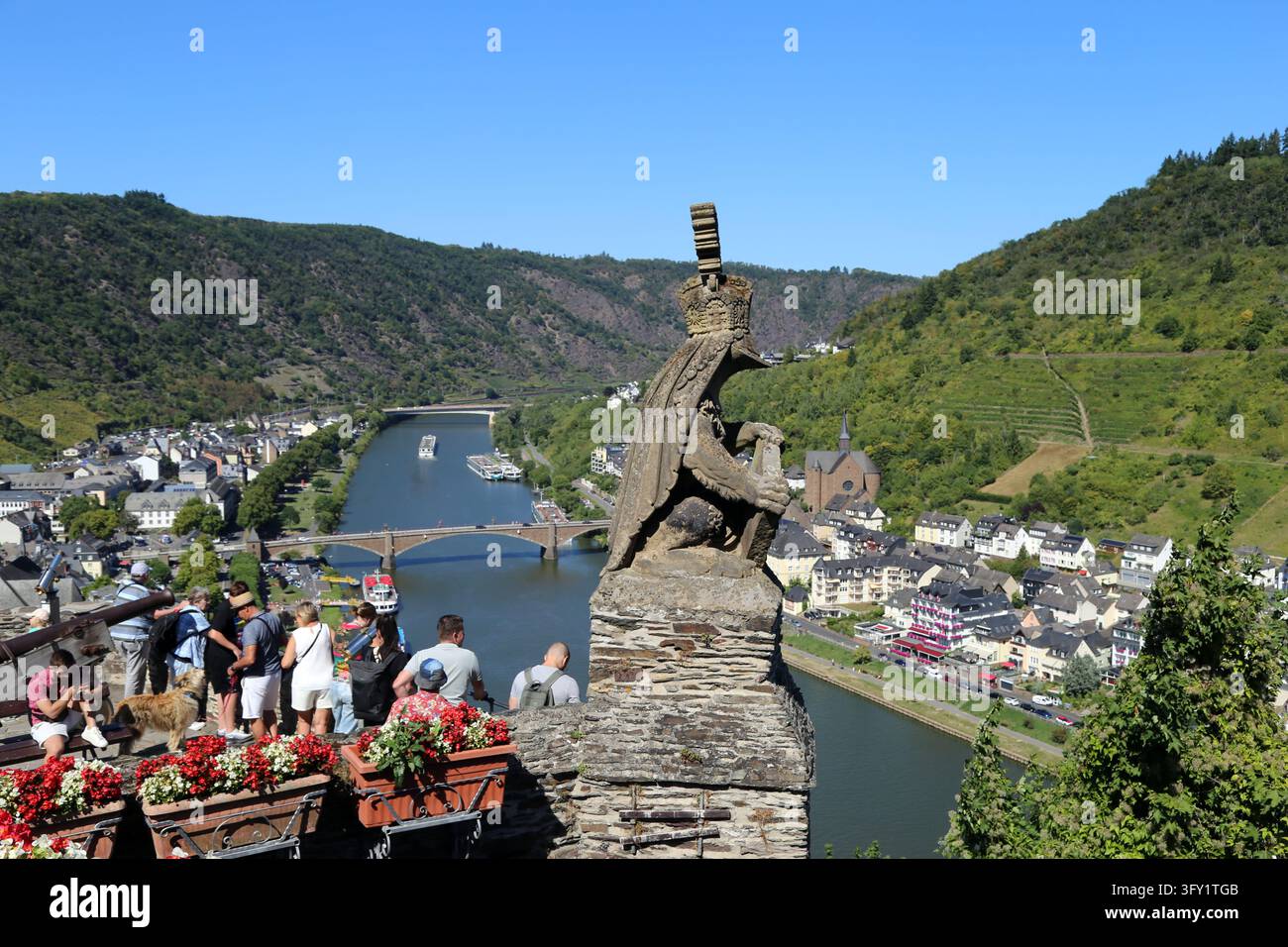 Vista panoramica del fiume Mosella, del ponte e della città dalla terrazza panoramica del Reichsburg Cochem con statua di rana incoronata e turisti, Germania. Foto Stock