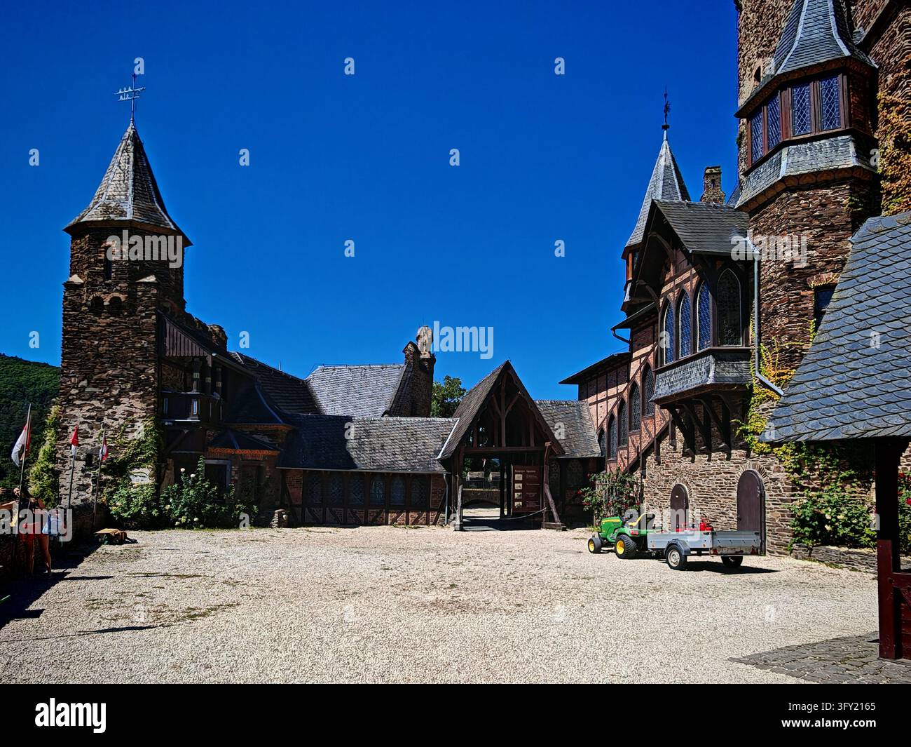 Cortile interno pittoresco dell'historica roccaforte medievale di Reichsburg Cochem con torri in pietra sotto un cielo blu a Cochem, Germania. Foto Stock