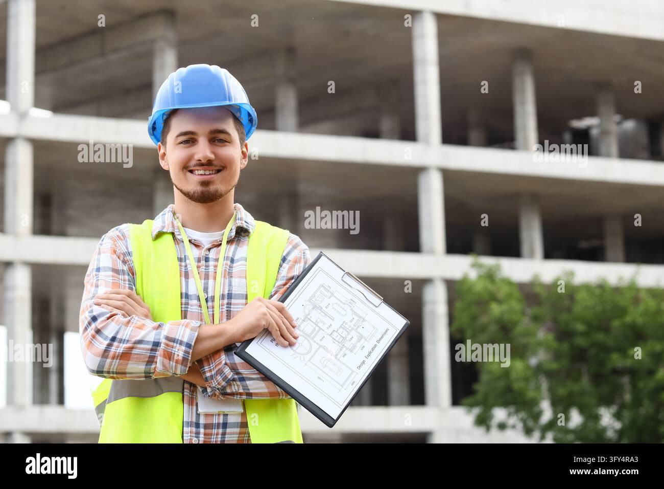 Gestione e ingegneria della costruzione, architetto sorridente con progetto in cantiere, imprenditore professionale con attrezzatura di sicurezza per lo sviluppo urbano Foto Stock