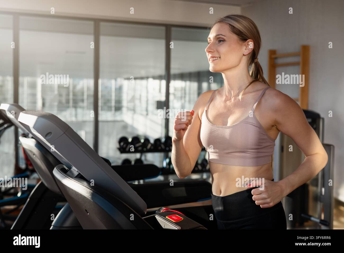 Donna determinata che corre su un tapis roulant in palestra Foto Stock