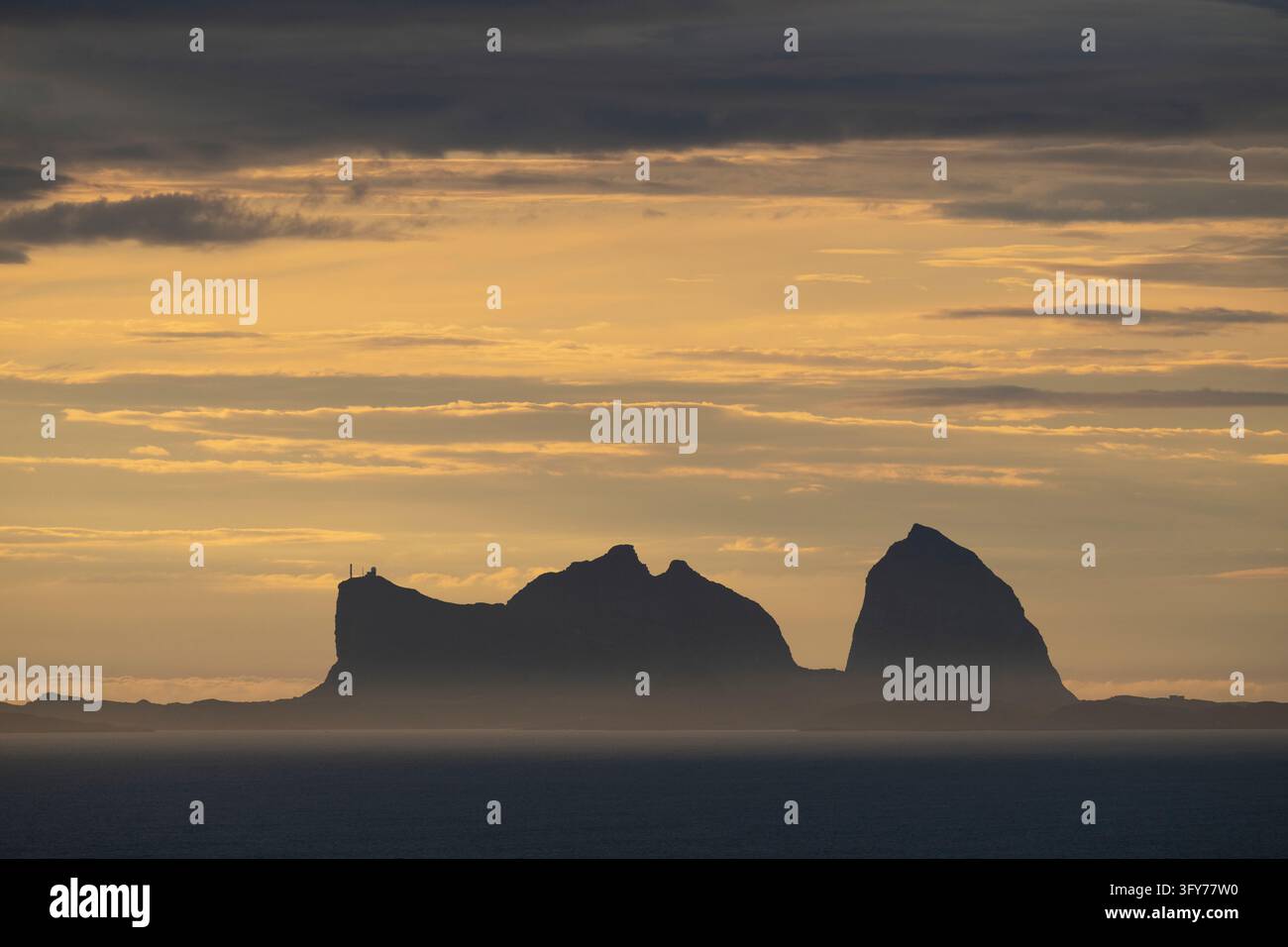 Le vette iconiche delle montagne di Sanna Træna si ergono nel cielo serale come appaiono Foto Stock