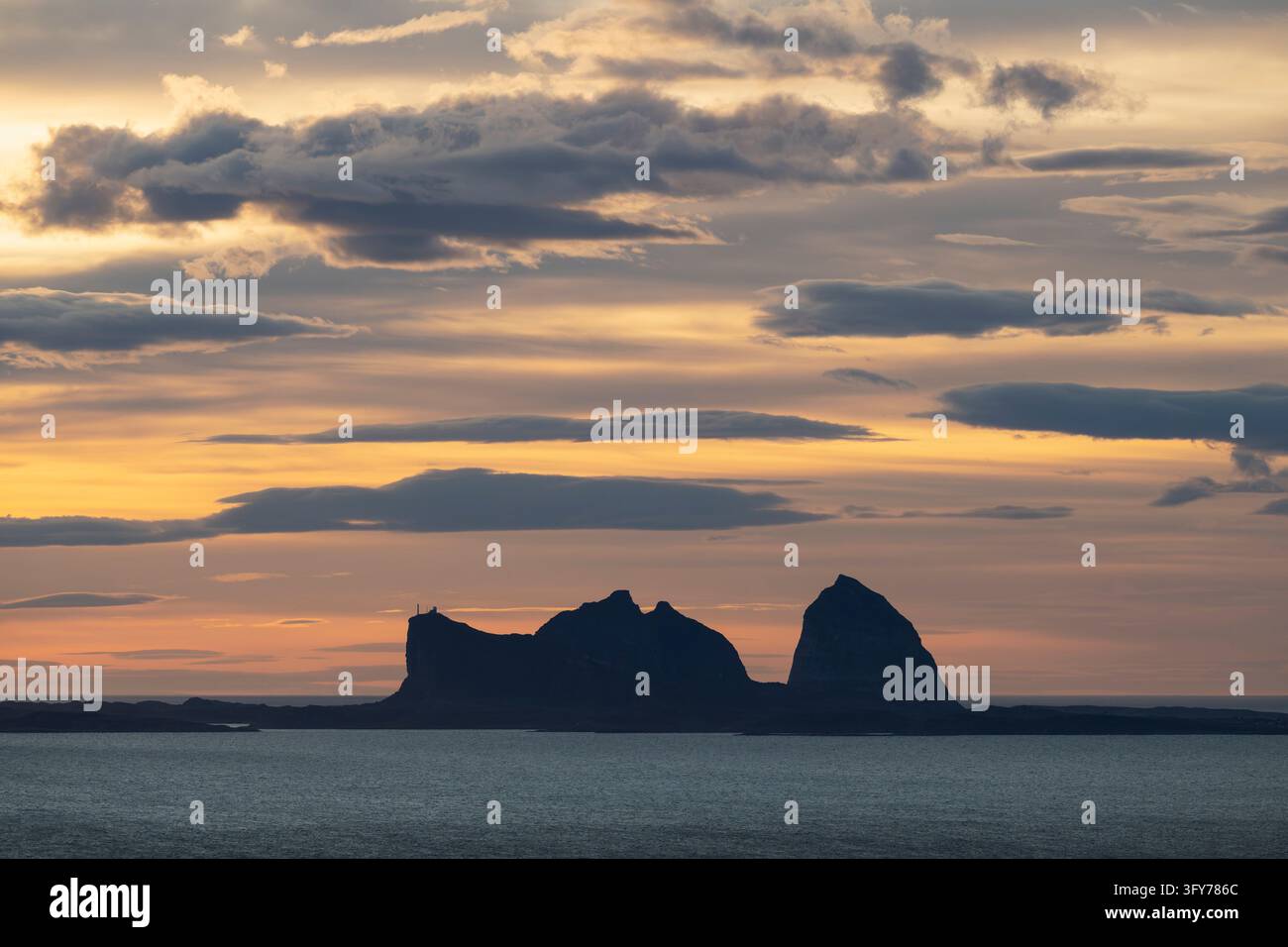 Le cime iconiche delle montagne di Sanna Træna si ergono nel cielo serale come viste Foto Stock