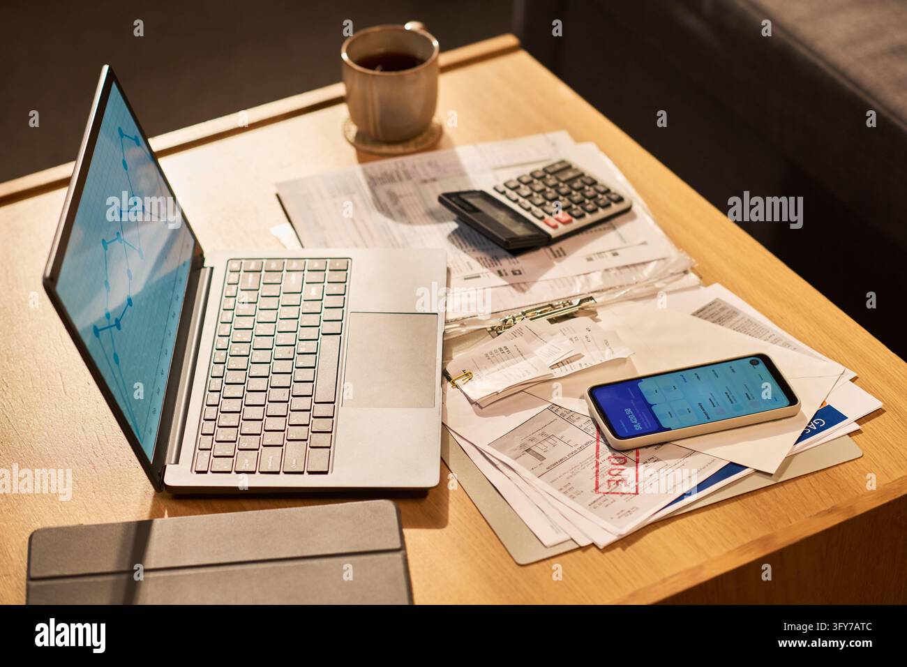 Portatile che mostra grafici finanziari con fatture sulla scrivania Foto Stock