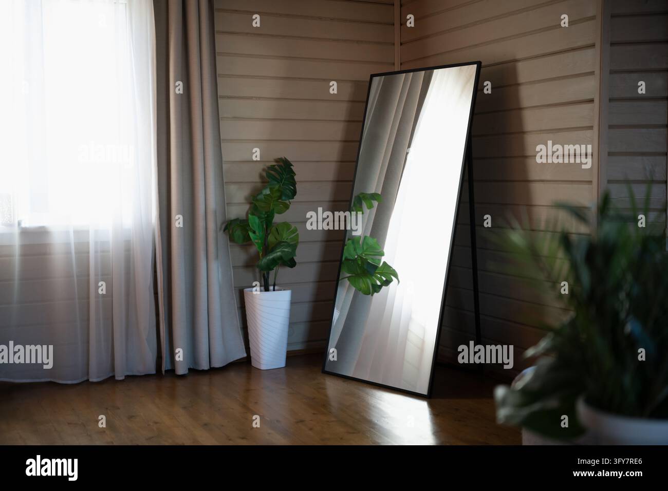 Specchio a pavimento a tutta lunghezza che riflette una finestra in un interno di casa in legno Foto Stock