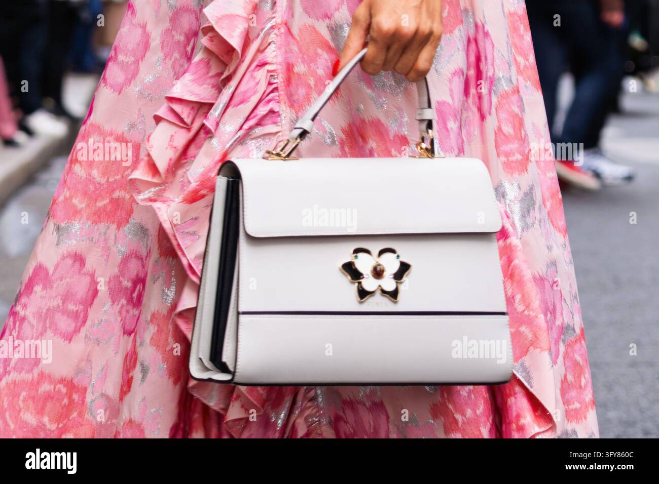 Parigi, Francia - 2 ottobre 2021: Donna indossa una borsa a spalla in pelle bianca Furla con un vestito floreale rosa a balze. Dettagli di borsa dell'abbigliamento alla moda, stra Foto Stock