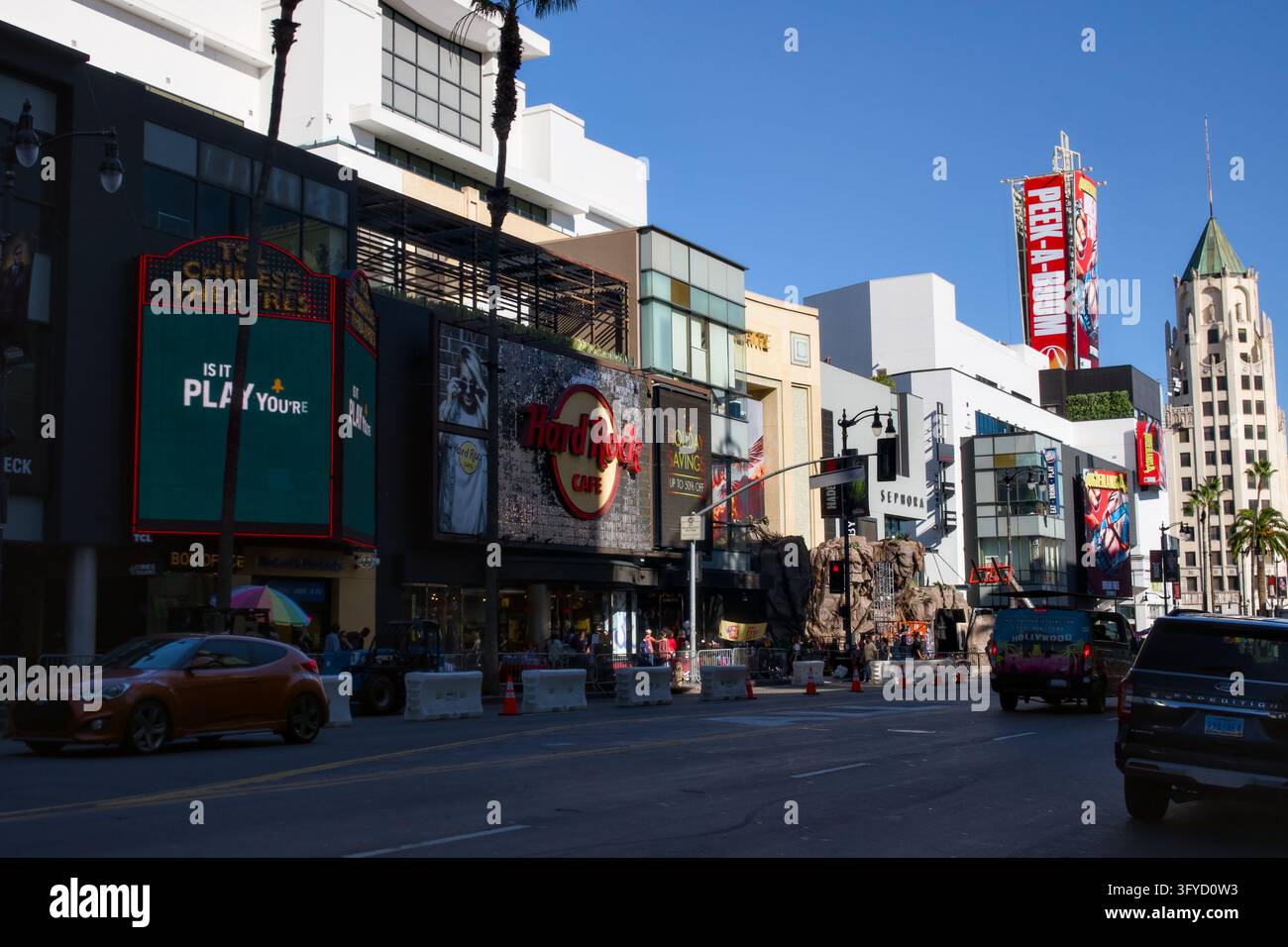Holywood Stati Uniti 23 ottobre 2026 Il traffico passa davanti al Hard Rock Cafe, al TCL Chinese Theatre e a una torre di chiesa storica sotto un cielo blu terso Foto Stock