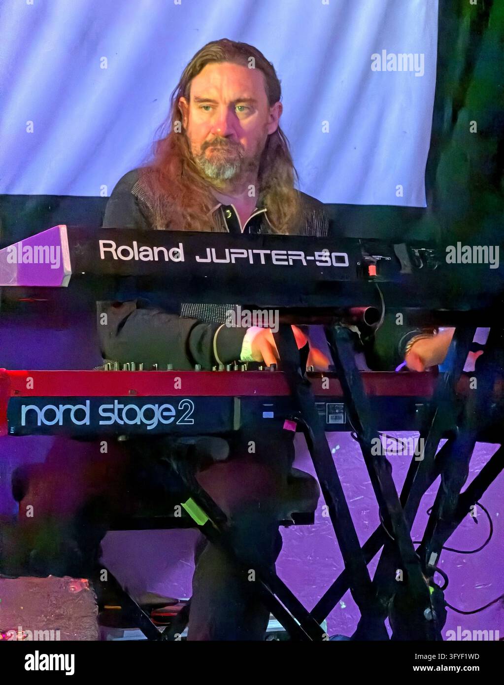 Il musicista Matt Steele si trova dietro un Roland Jupiter-50 e una tastiera Nord Stage 2, concentrato su una performance dal vivo degli A Certain Ratio Foto Stock