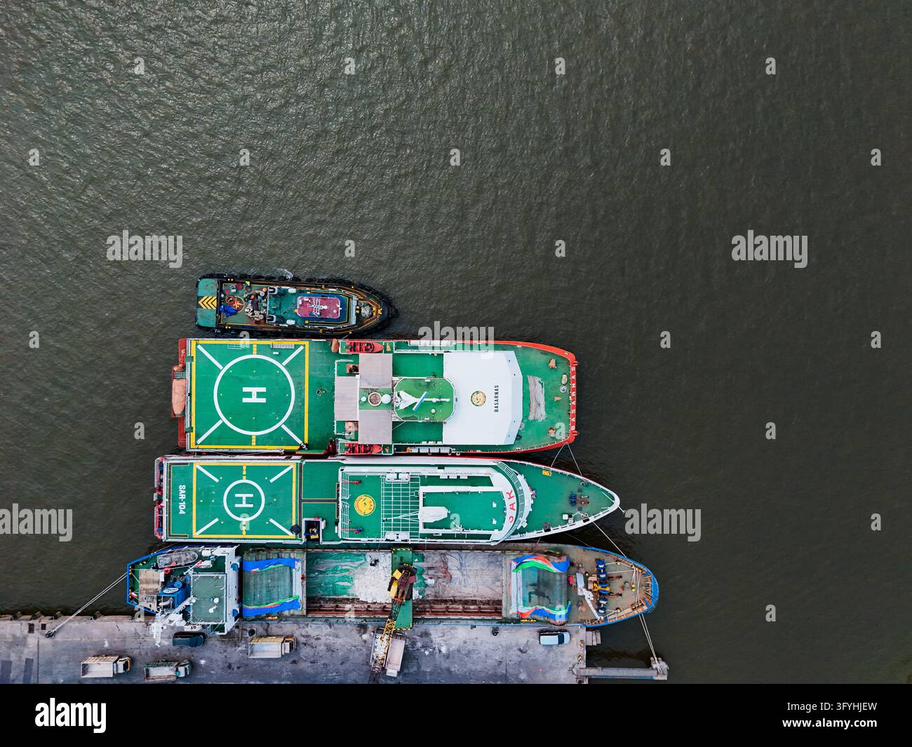 Vista aerea del porto di Trisakti con varie navi, tra cui rimorchiatori e navi di rifornimento con eliporti ormeggiati lungo il molo a Kecamatan Banjarmasin Bar Foto Stock