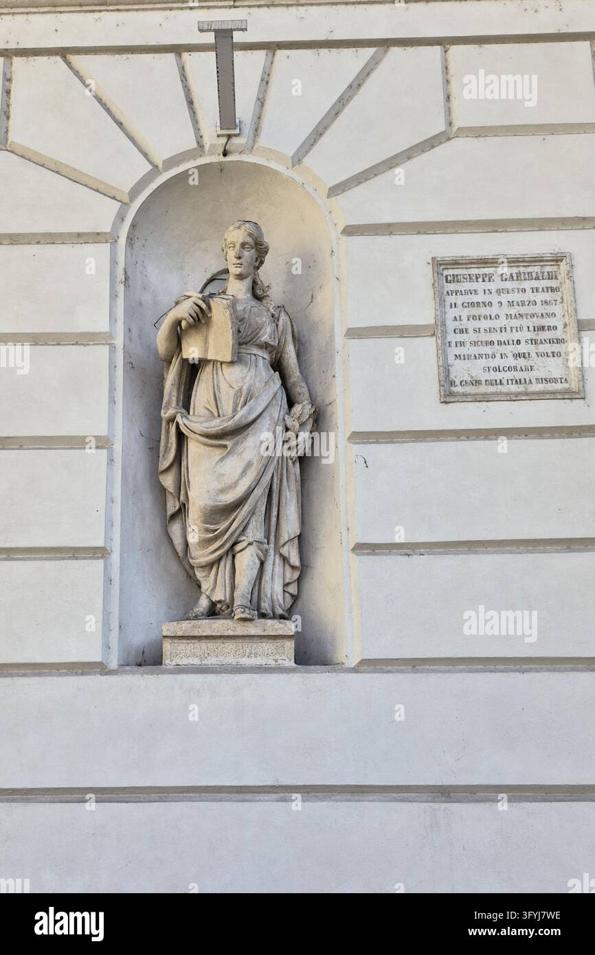 Statua allegorica in marmo in una nicchia murale ad arco accanto a una targa commemorativa dedicata a Giuseppe Garibaldi sul Teatro Sociale Foto Stock