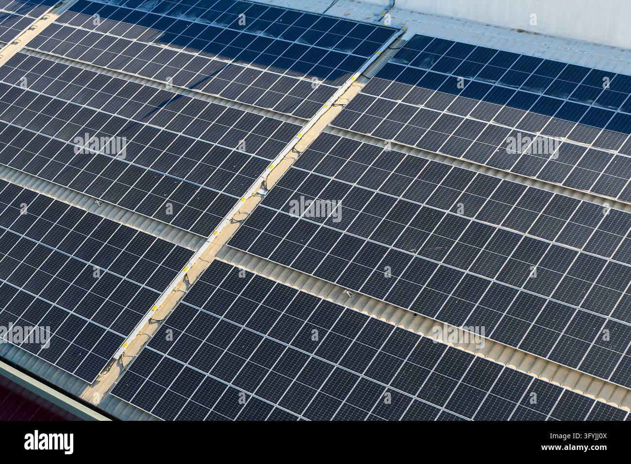 Ampia disposizione di pannelli solari fotovoltaici che coprono il tetto di un edificio industriale, generando energia elettrica pulita attraverso la tecnologia di energia solare rinnovabile Foto Stock