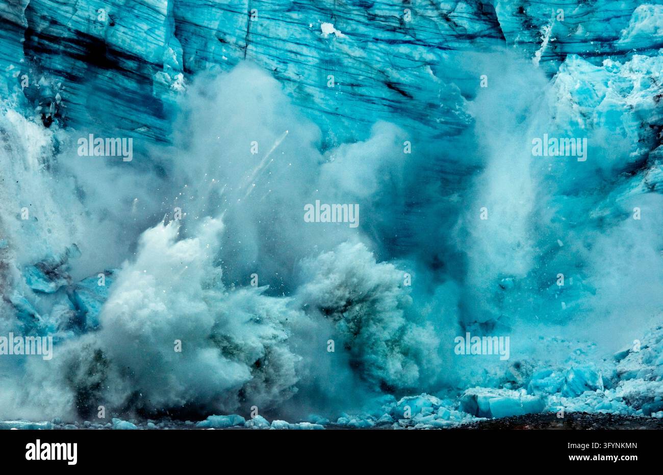 Una vista drammatica dello scioglimento di un ghiacciaio al Glacier Bay National Park & Preserve in Alaska, USA. Enormi blocchi e seracchi di antica ice glaciolare blu si staccano dall'enorme terminazione del ghiacciaio marino e si schiantano nelle acque fredde del fiordo sottostante, generando grandi onde e iceberg galleggianti. Questo fenomeno geologico naturale illustra la dinamica dei ghiacci e gli ambienti di natura costiera, dove i visitatori devono prepararsi a temperature fresche e condizioni meteorologiche in rapido cambiamento in mezzo a paesaggi spettacolari. Una versione ottimizzata di un'immagine del US National Park Service. Credit: NPS Foto Stock