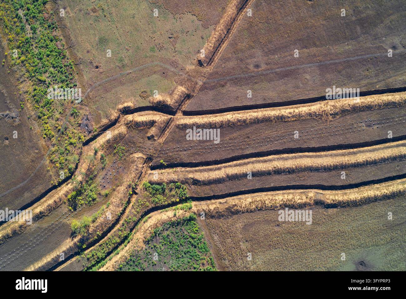 Vista aerea dall'alto di trincee di fortificazione militare, opere di difesa in terra e barriere scavate su terreni agricoli, che mostrano preparativi difensivi e strutture di ingegneria da campo di battaglia. Foto Stock