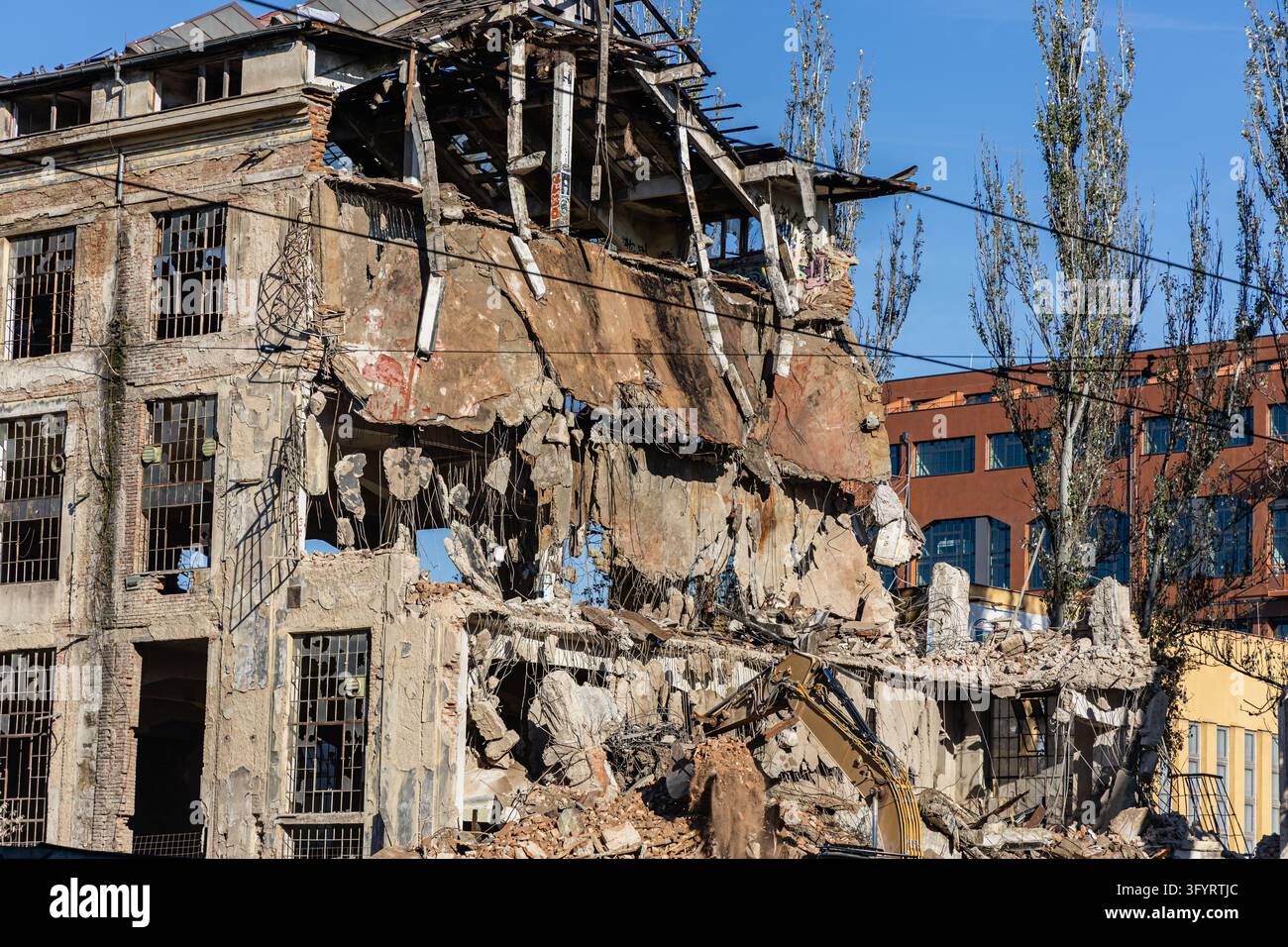 Escavatore pesante rimuove i detriti da un edificio industriale in decadenza a Praga. Scena di riqualificazione urbana con spazio per copia adatto a costruzione, demolizione Foto Stock
