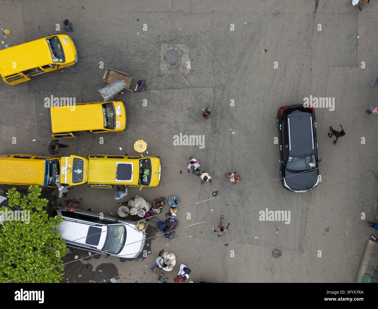 Vista aerea di autobus danfo gialli e auto che percorrono una strada trafficata con pedoni a Lagos, Lagos, Nigeria. Foto Stock