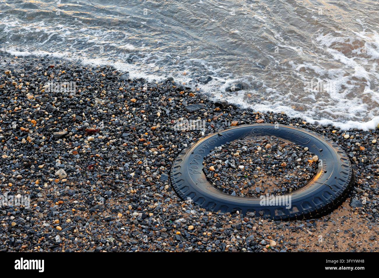 Un pneumatico radiale Firestone Transteel spiaggiato su una spiaggia coperta di sabbia e ghiaia. East River, Manhattan, New York City Foto Stock