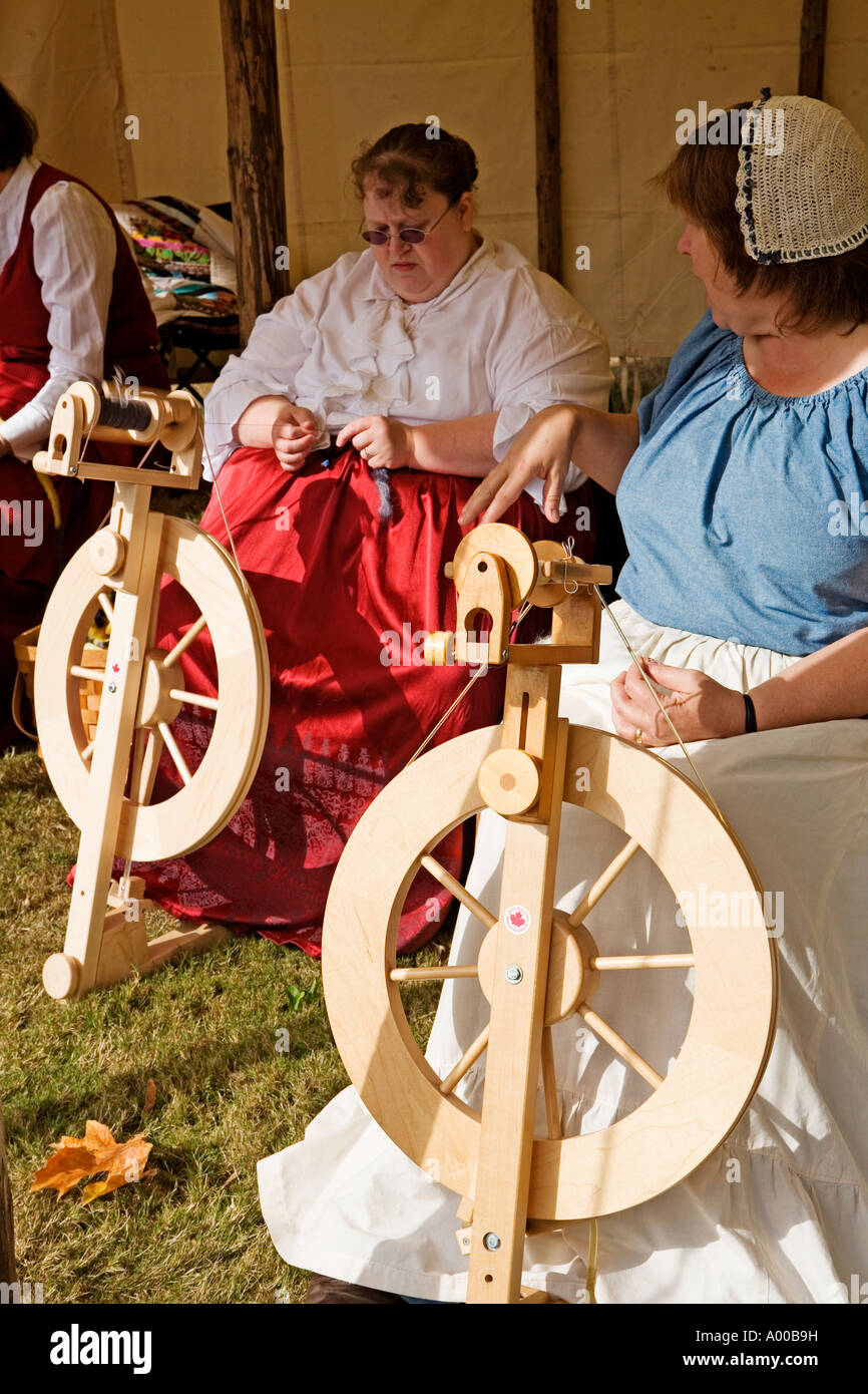 Immagine di un gruppo di quattro donne vestite di Pioneer abbigliamento tutti lavorando la filatura ruote sotto una tenda Foto Stock