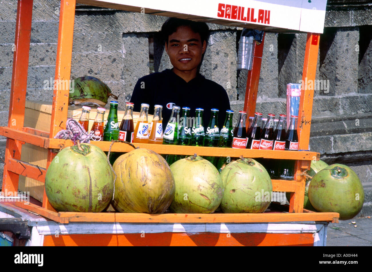 Sorridente uomo locale con il suo cibo carrello di succhi di frutta e acqua di meloni vicino a Denpasar Bali Indonesia Foto Stock