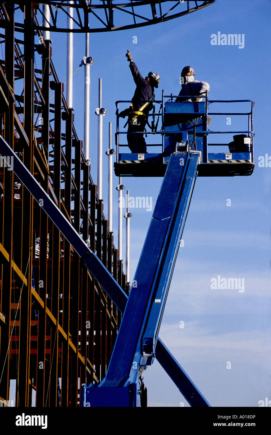 Lavoratori edili sul dispositivo di sollevamento aereo guardando acciaio strutturale Foto Stock