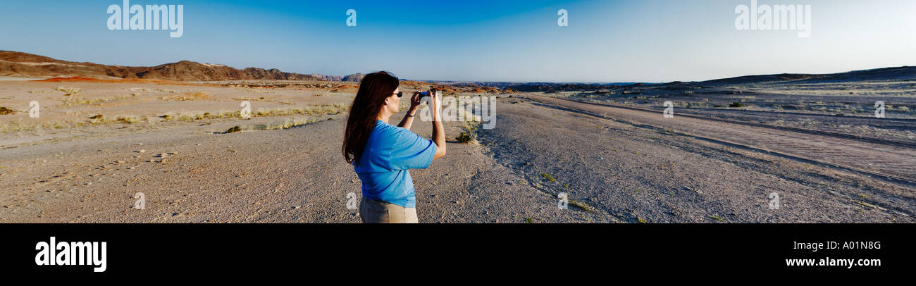 Turistica prendendo una foto del vasto paesaggio arido in Namibia Modello rilasciato Foto Stock