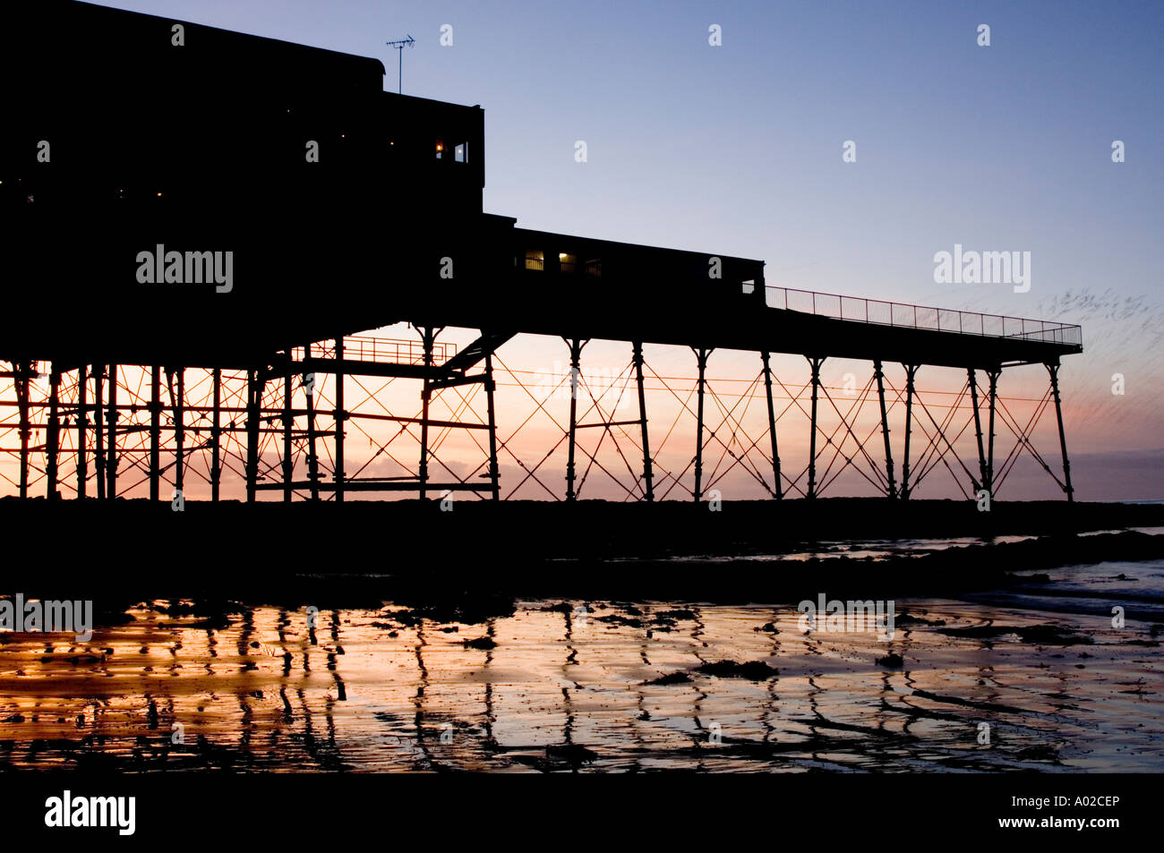 Aberystwyth molo al tramonto - Architettura vittoriana - tronco dalla tempesta e fuoco negli anni trenta Foto Stock