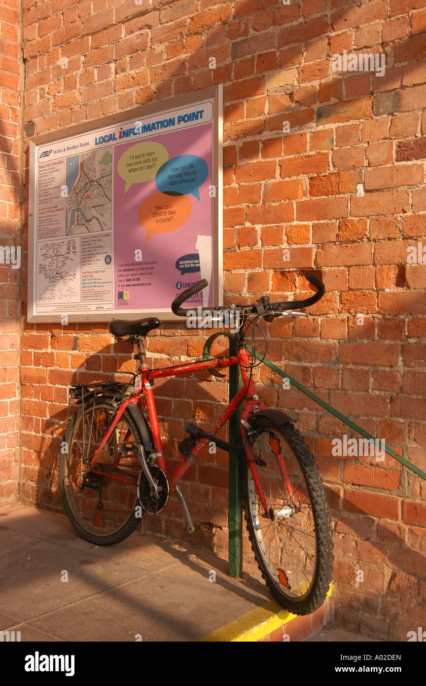 Bike puntellato contro un muro di mattoni Aberystwyth stazione ferroviaria pomeriggio estivo Wales UK Foto Stock