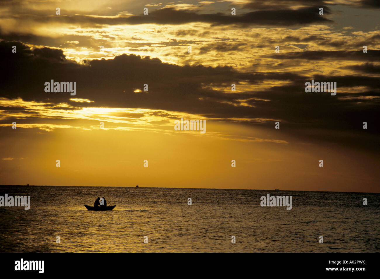 I pescatori in una barca a remi profilarsi all'alba. Foto Stock