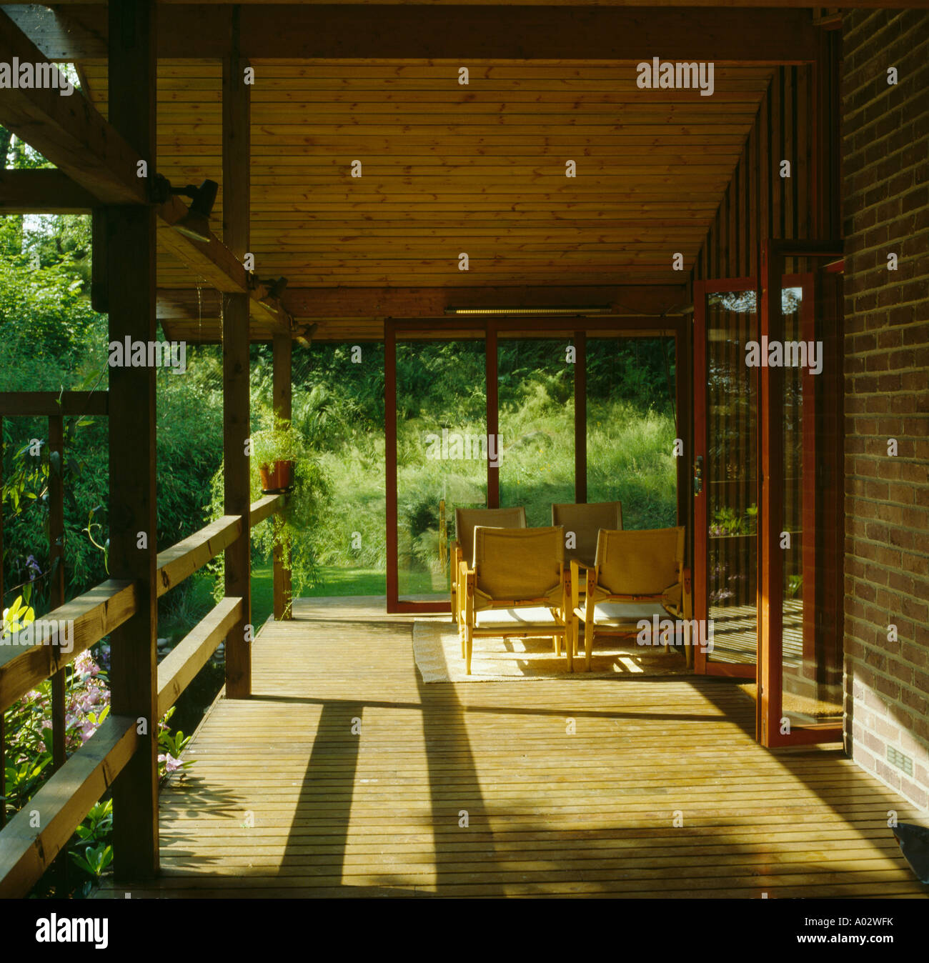 Moderna veranda in legno con sedie e vista del giardino Foto Stock