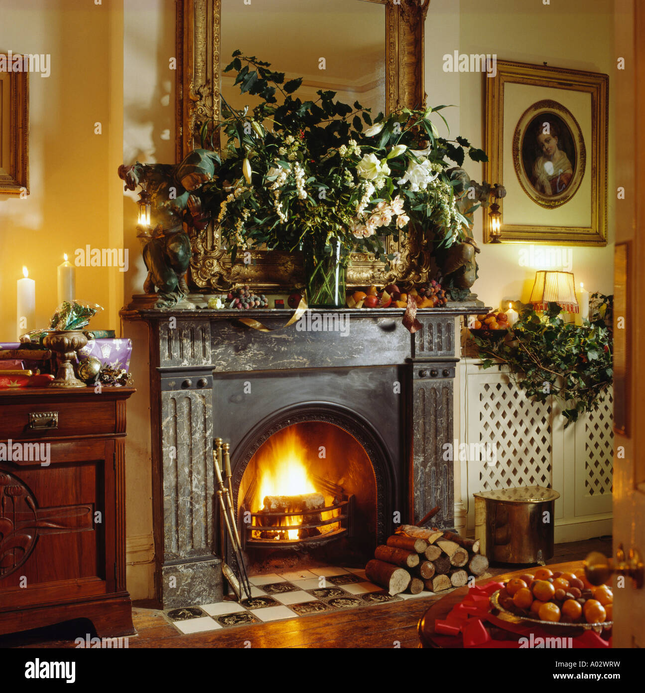 Ghisa camino tradizionale in Natale livingroom con candele accese e fuoco e  foglie verdi in vaso a mantelpiece Foto stock - Alamy