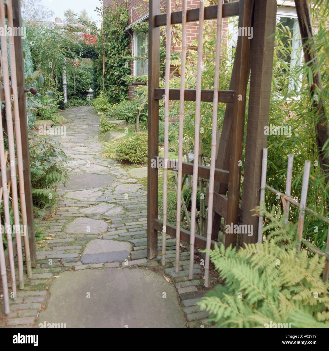 Aprire il cancello di bambù con vista del sentiero lastricato e lo stile orientale di giardino Foto Stock